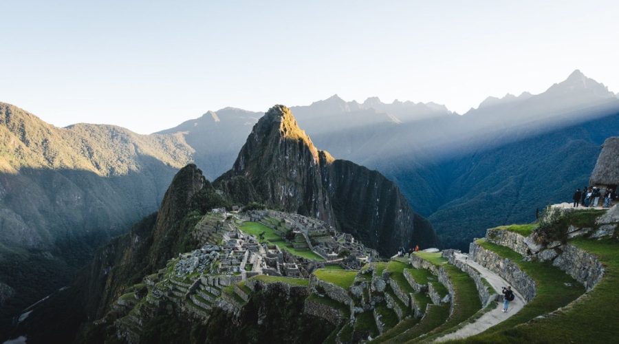 A scenic view of Machu Picchu, showcasing ancient stone structures and terraces amidst lush mountains under a clear sky. Enhance your experience with guided tours and activities, and remember that tour guide tipping is a meaningful gesture to show appreciation.